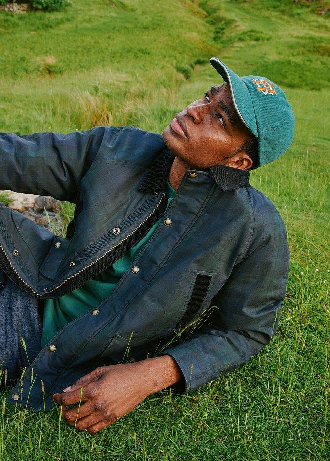 a man in a blue jacket sitting on the grass with a dog